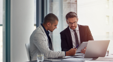 two executives reviewing documents and a tablet