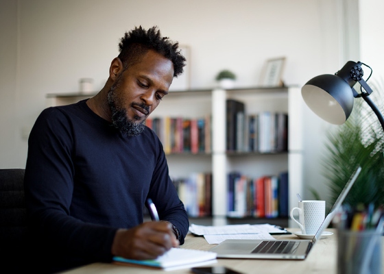 a man writing on a pad on his desk