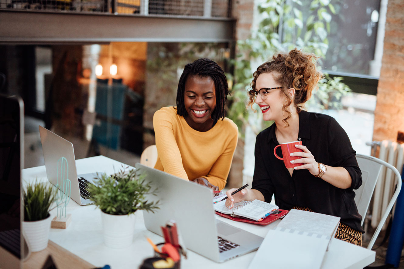 Two female coworkers at desk.